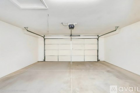 A spacious garage with a white door and a concrete floor.