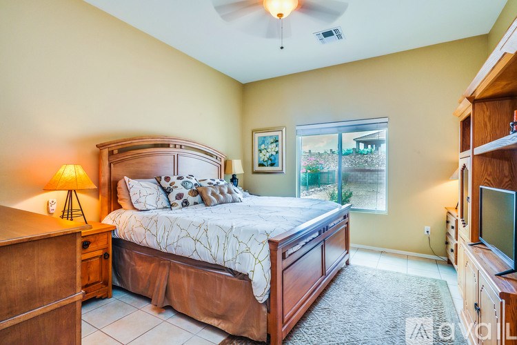 A bedroom with a large bed, a ceiling fan, and a window overlooking a garden.