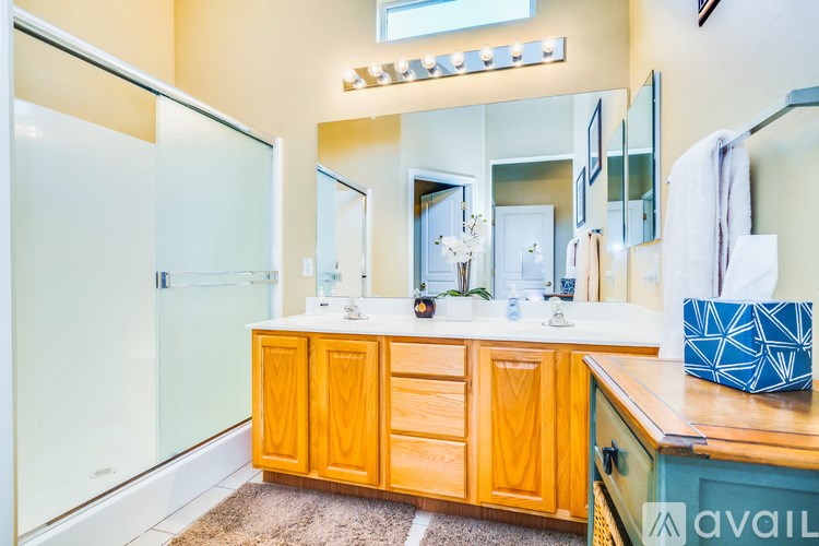 A bathroom with wooden cabinets and a glass shower door.