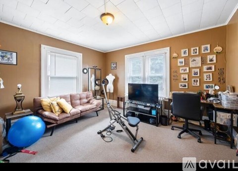 A living room with a brown couch, a blue exercise ball, and a television.