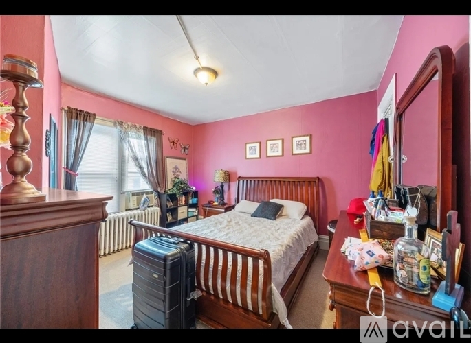 A bedroom with a bed, dresser, and suitcase.