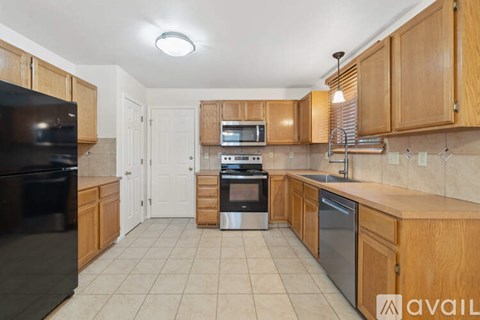 A kitchen with wooden cabinets and black appliances is available for rent.