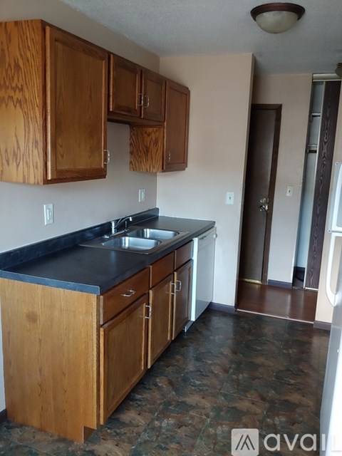 A kitchen with wooden cabinets and a black counter top.