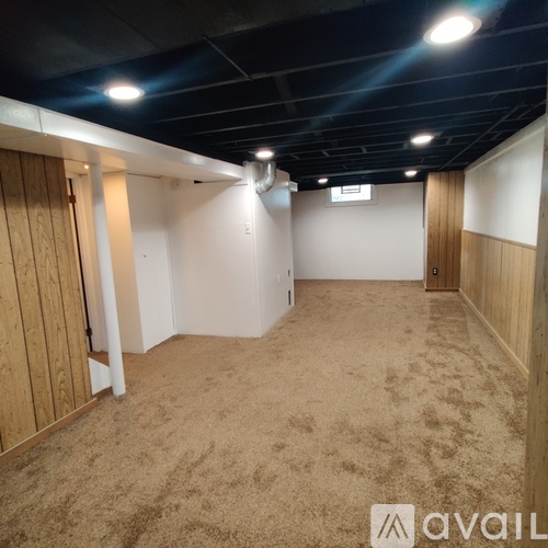 A spacious room with carpeted floor and wooden walls.