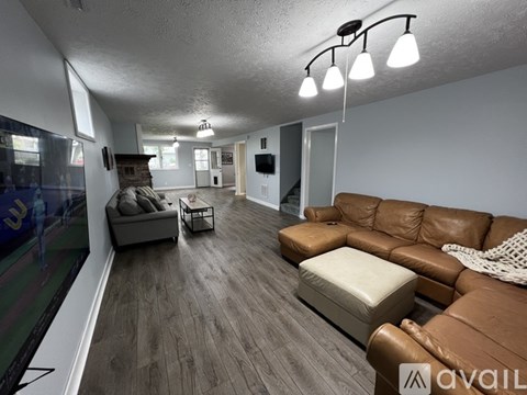 A living room with a brown leather couch and a white ottoman.