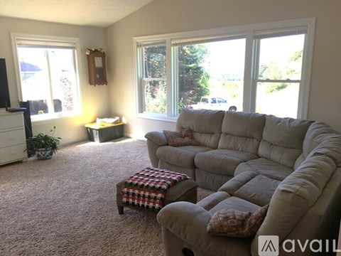 A living room with a grey couch and a small table with a plaid blanket on it.