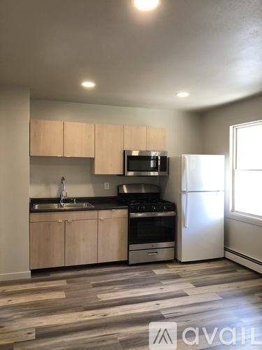 A kitchen with a stove, sink, and refrigerator.