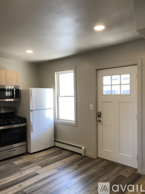 A kitchen with a white fridge and a white door.