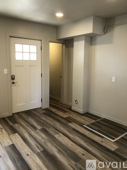 A room with a white door and a wooden floor.