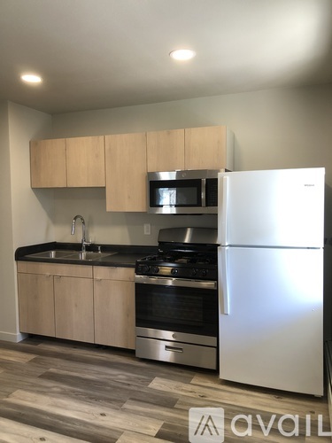 A kitchen with a refrigerator, sink, and stove.