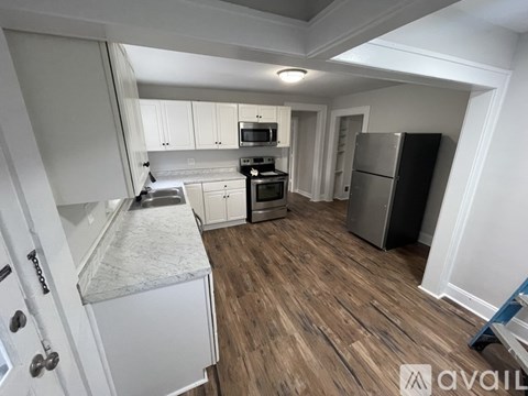 A kitchen with white cabinets and a wooden floor.