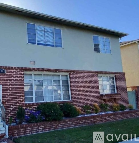 A house with a grey roof and a brick wall with windows and plants.