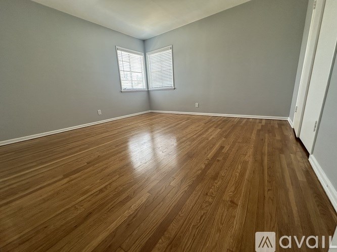 A room with wooden flooring and a window with blinds.