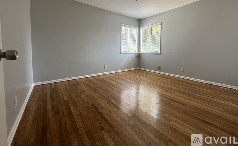 A room with wooden flooring and a window with blinds.