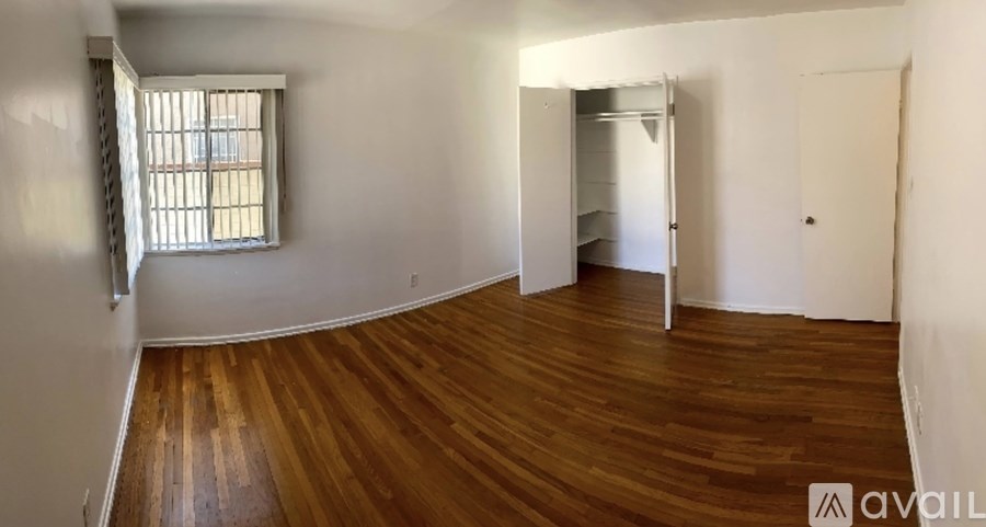 A room with wooden flooring and a window with bars on it.