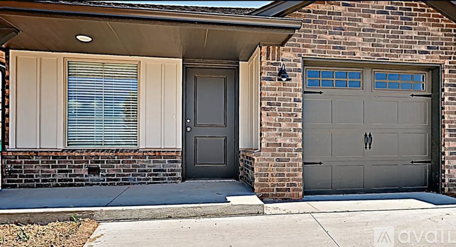 A house with a grey garage door and a brown brick wall.