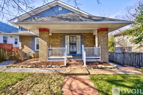 A house with a blue roof and a brick front porch.