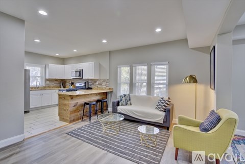 A living room with a yellow chair and a white couch.