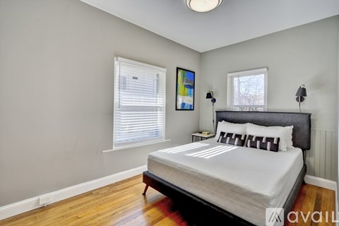 A bedroom with a bed, two lamps, and a window with blinds.