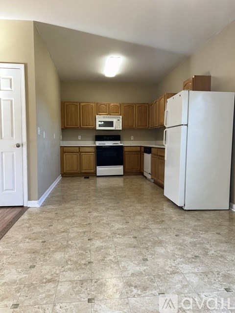 A kitchen with a white refrigerator and wooden cabinets.