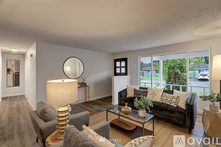 A living room with a grey couch, a coffee table, and a lamp.