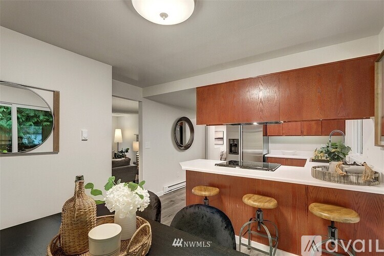 A kitchen with a bar stool and a counter with a vase of flowers on it.