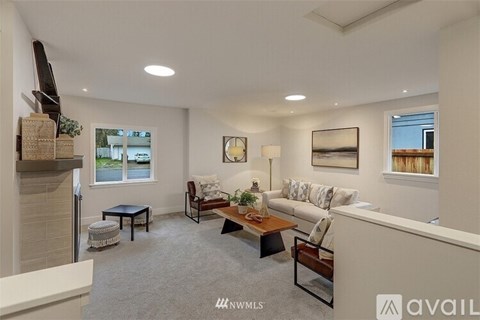 A living room with a grey carpet and a white wall.