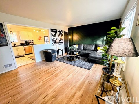 A living room with a black couch and a wooden floor.