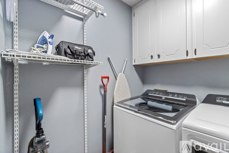 A white ironing board is leaning against a wall in a laundry room.