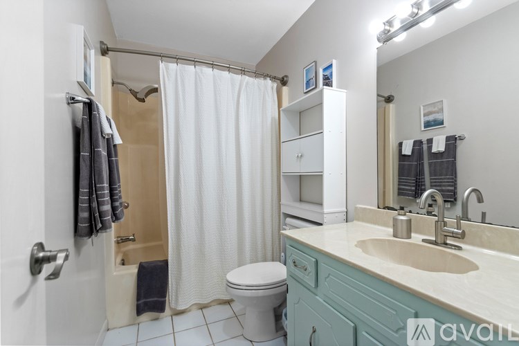 A bathroom with a white toilet, a sink, and a shower with a white curtain.