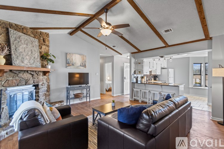 A living room with a stone fireplace and a brown leather couch.