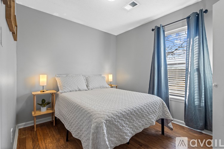 A bedroom with a bed, nightstand, and window with curtains.