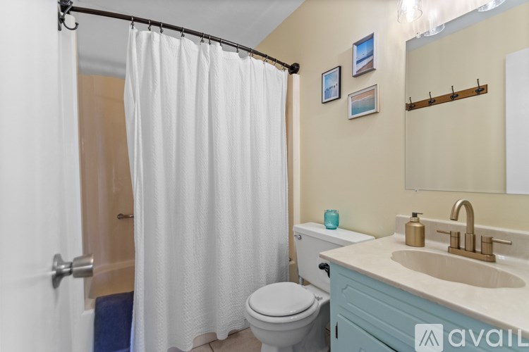 A bathroom with a toilet, sink, and shower curtain.