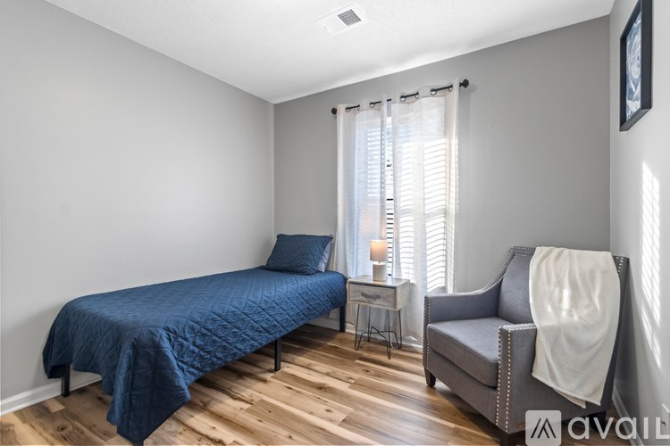 A bedroom with a bed, chair, and window.