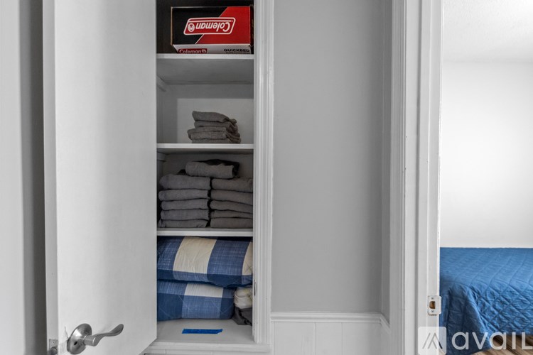 A white closet with towels and a red box on top.
