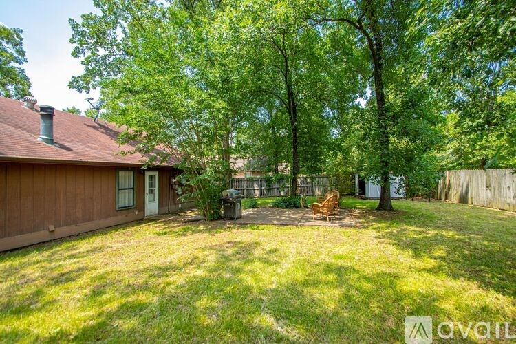 A backyard with a lawn, trees, and a small house.