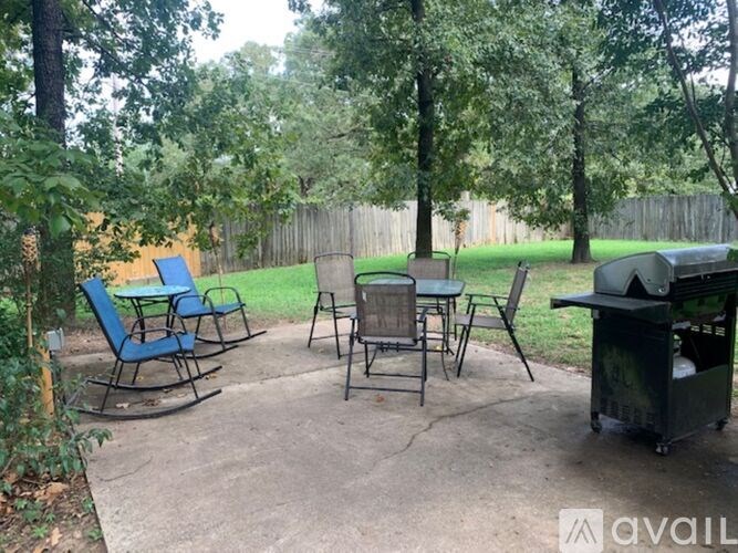 A backyard with a black grill and a blue chair.