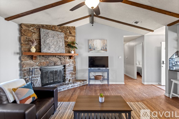 A living room with a stone fireplace and a brown leather couch.