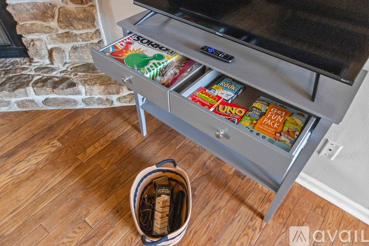 A drawer full of snacks and a remote control on top of a TV stand.
