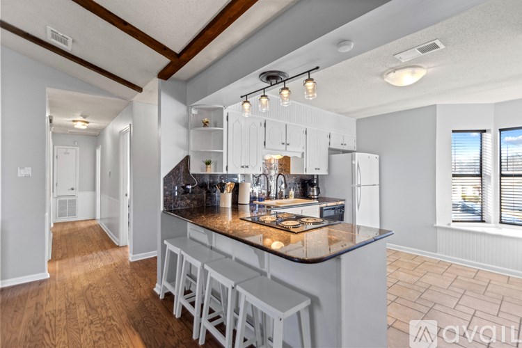 A kitchen with a wooden floor and white cabinets.