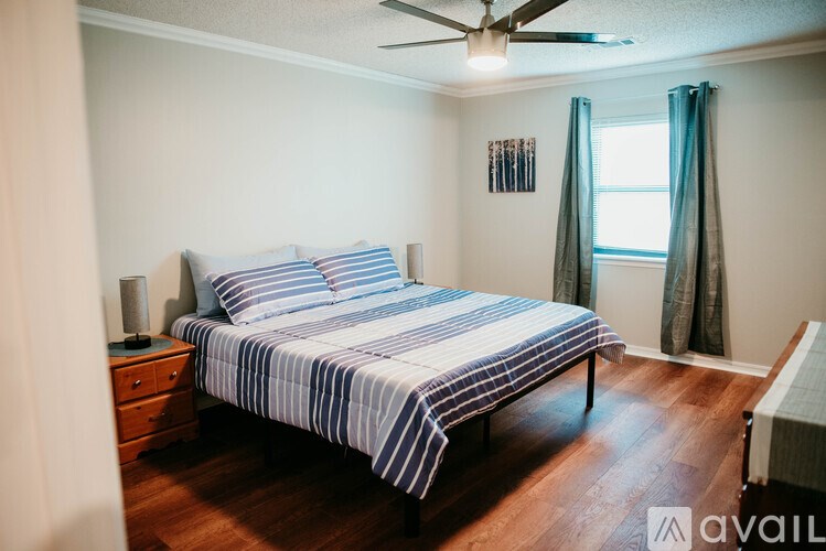 A bedroom with a bed, nightstand, and window.