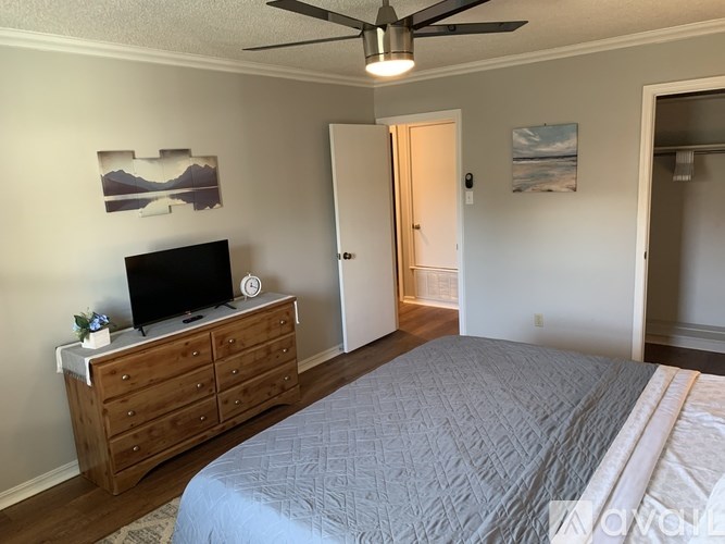 A bedroom with a bed, dresser, and ceiling fan.