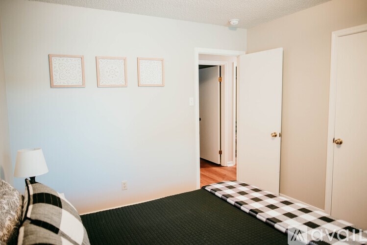 A room with a black and white checkered bedspread and a lamp on a bedside table.