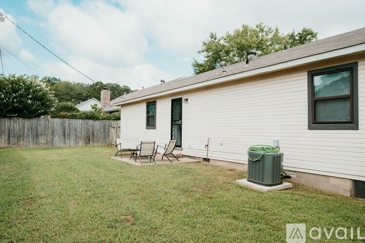 A small white house with a green trash can in front of it.