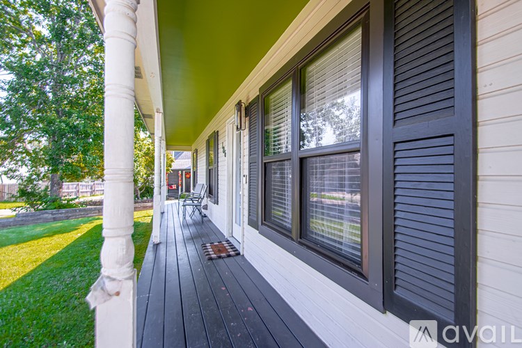 A porch with a green ceiling and a white column.