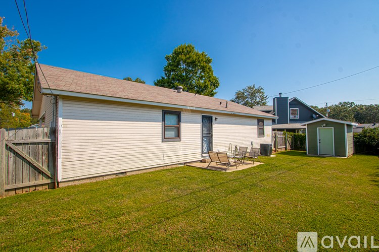 A house with a white exterior and a brown roof is surrounded by a green lawn.