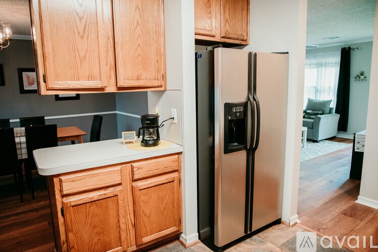 A kitchen with a refrigerator and wooden cabinets.