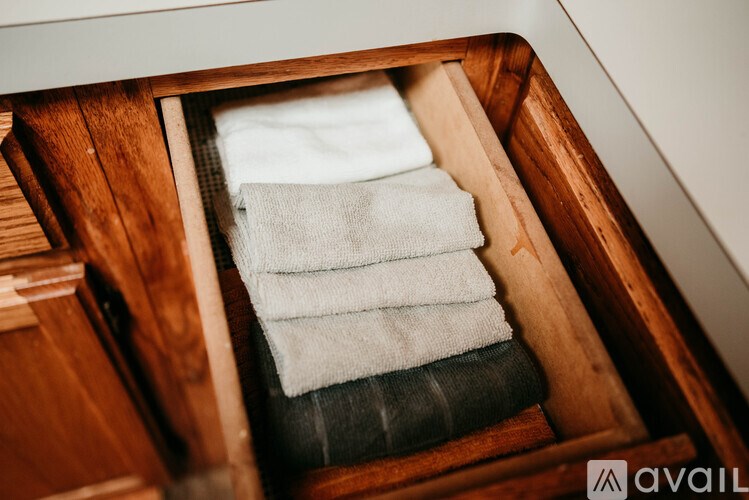 A stack of towels is neatly folded and placed in a wooden drawer.