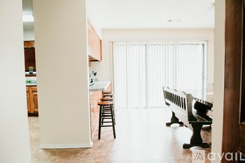 A kitchen with a dining table and chairs is visible through a doorway.
