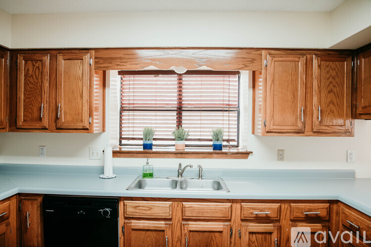 A kitchen with wooden cabinets and a black dishwasher.